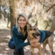 a woman in blue jacket smiling while embracing her dog